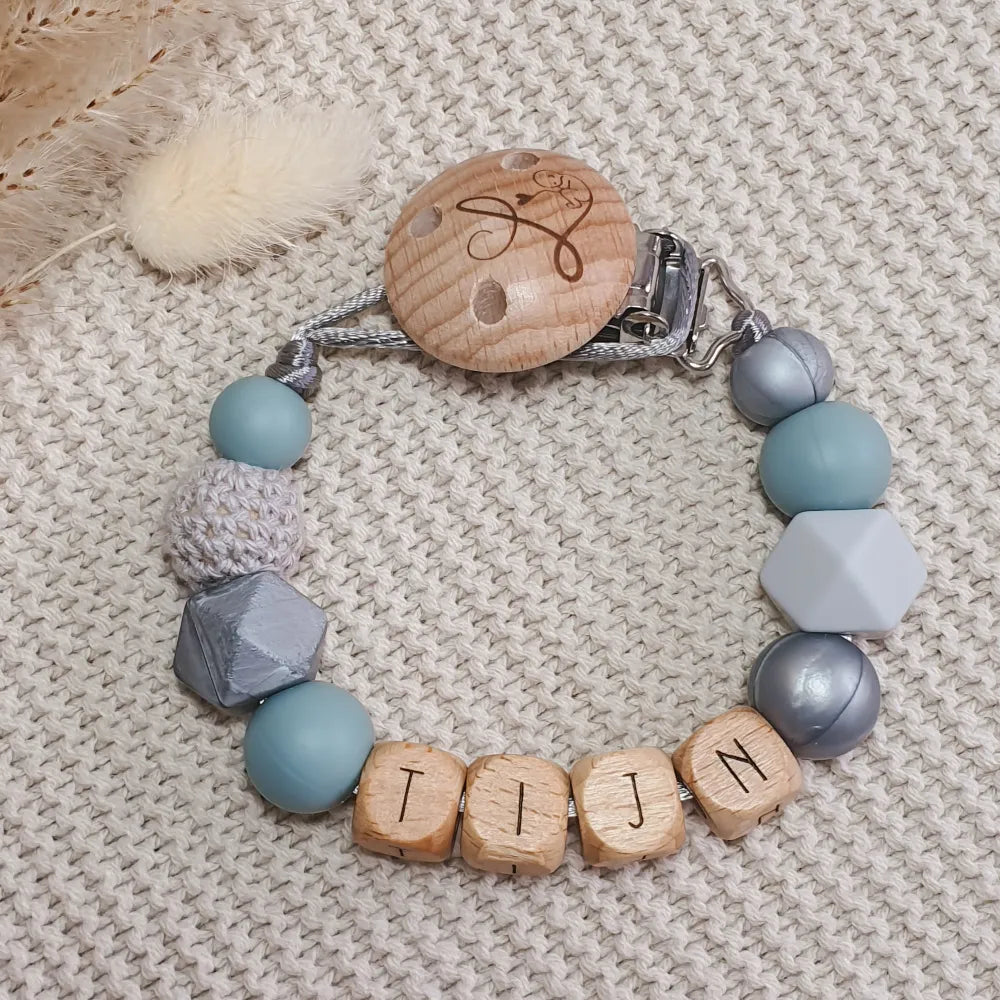 Gepersonaliseerd speenkoord met naam van houten letterkralen en siliconen kralen in blauw, zilver en grijs.