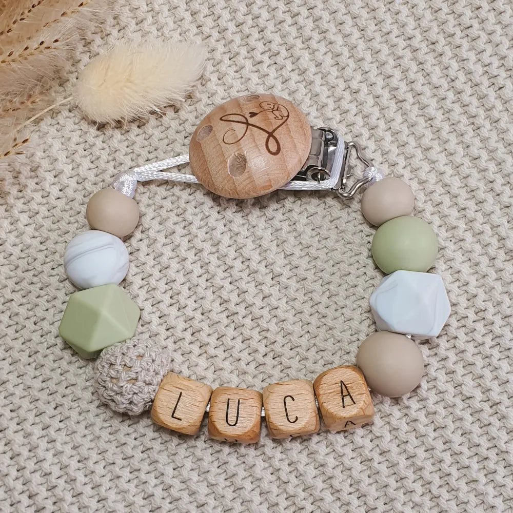 Gepersonaliseerd speenkoord met naam van houten letterkralen en siliconen kralen in groen, beige en marmer.
