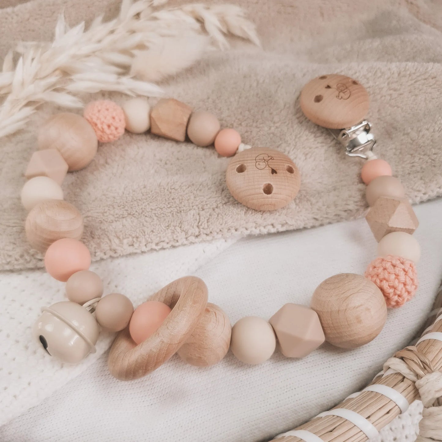 Wagenspanner in beige en zalmkleur met siliconen en houten kralen.