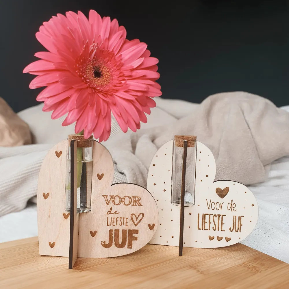 Twee houten bloemenhouders in de vorm van een hart gegraveerd met de tekst "Voor de liefste juf".