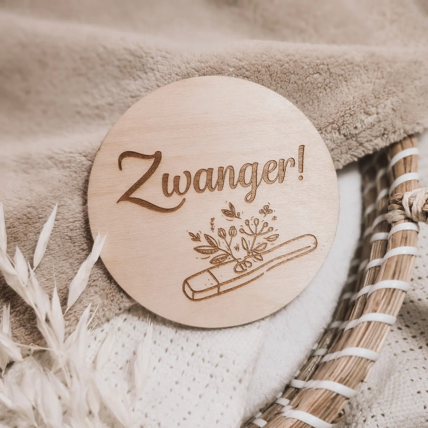 Houten aankondigingsbordje voor een zwangerschap, gegraveerd met de tekst "zwanger" en een zwangerschapstest waar plantjes uit groeien.