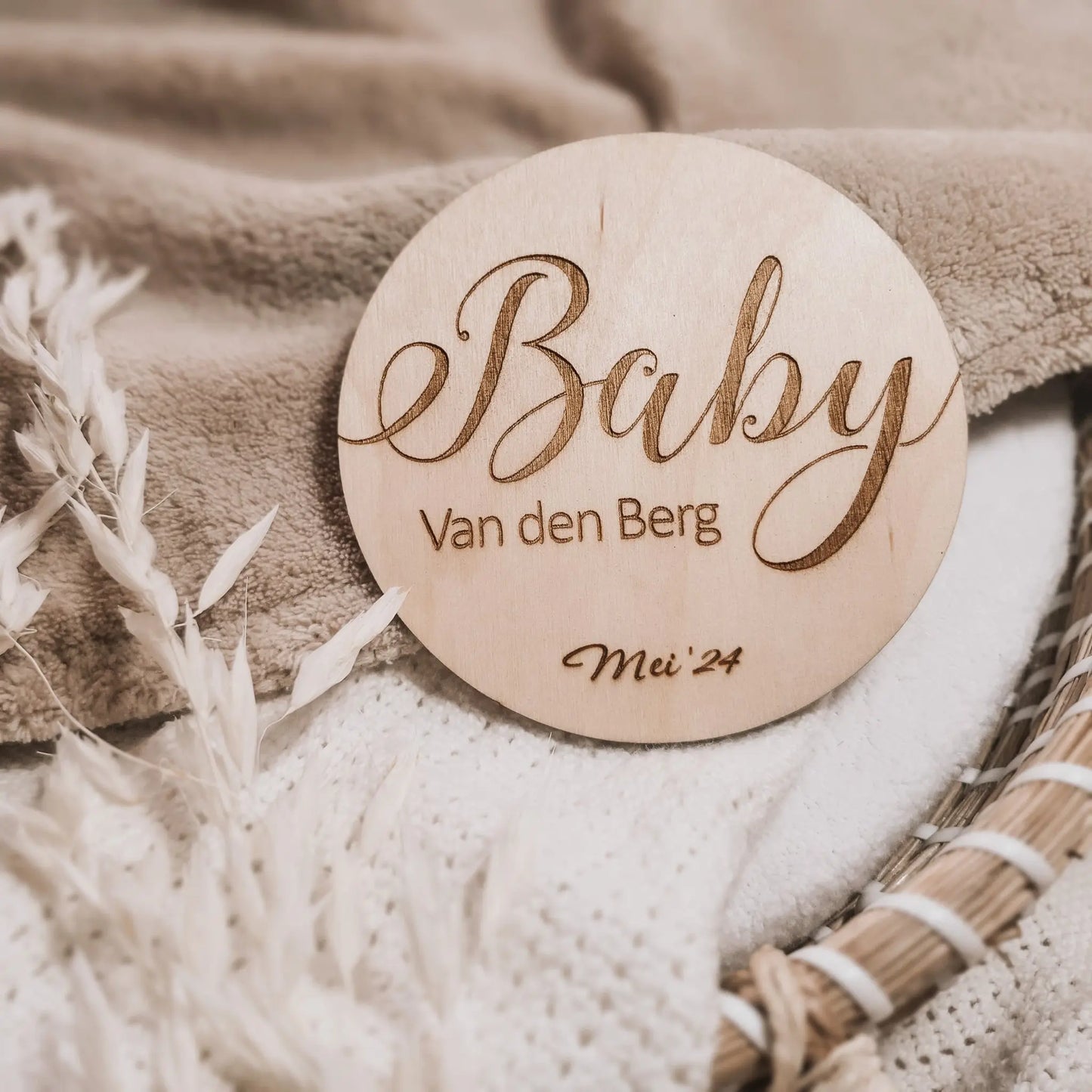 Houten aankondigingsbordje voor een zwangerschap, gegraveerd met de achternaam en uitgerekende datum.