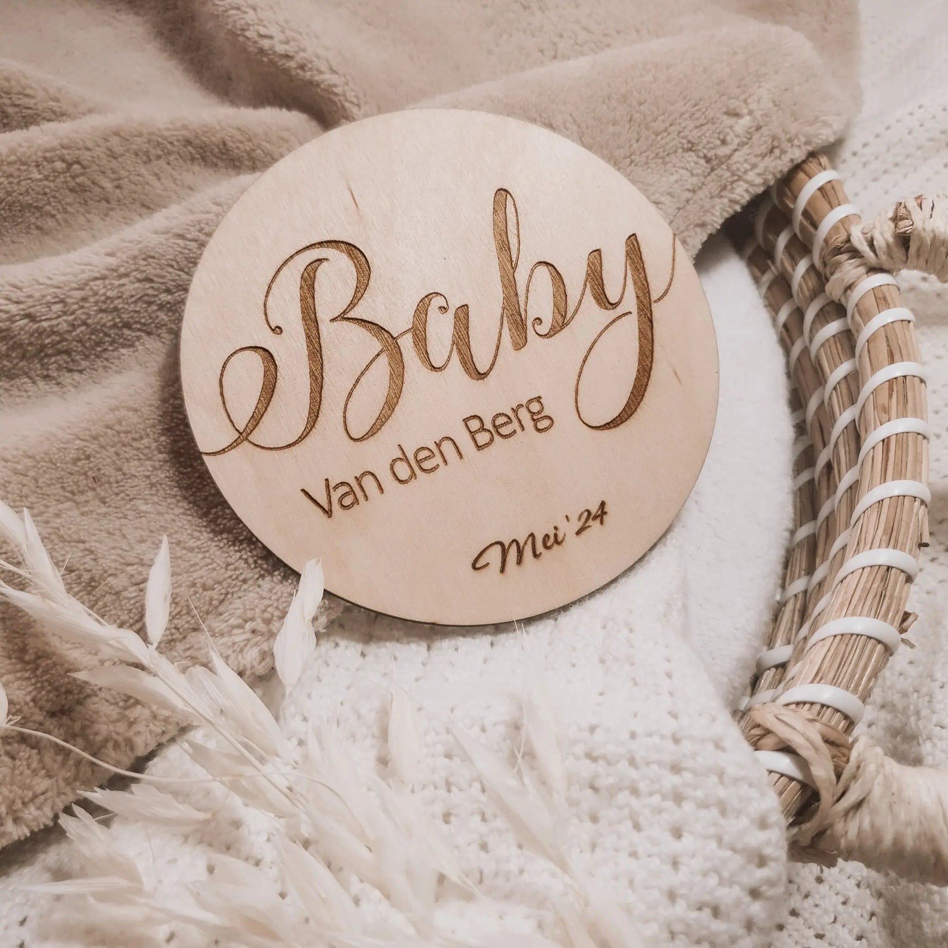 Houten aankondigingsbordje voor een zwangerschap, gegraveerd met de achternaam en uitgerekende datum.