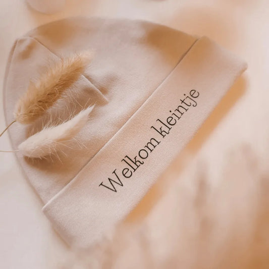 Beige babymutsje voor pasgeboren baby's, bedrukt met de tekst "Welkom kleintje".