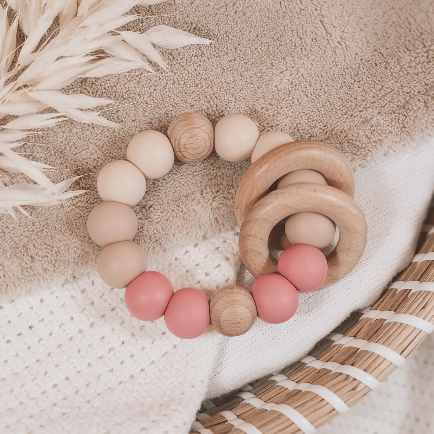 Siliconen bijtring in beige en oud roze met houten ringen en kralen.