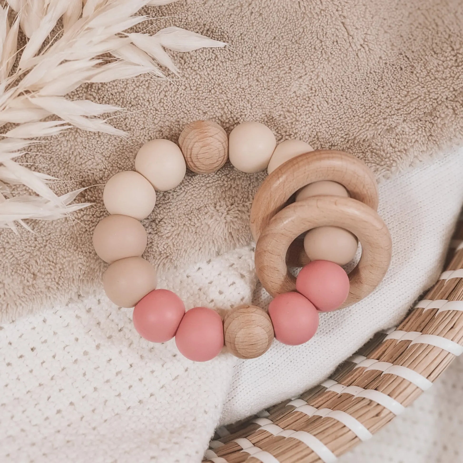 Siliconen bijtring in beige en oud roze met houten ringen en kralen.