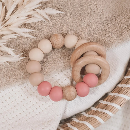 Siliconen bijtring in beige en oud roze met houten ringen en kralen.