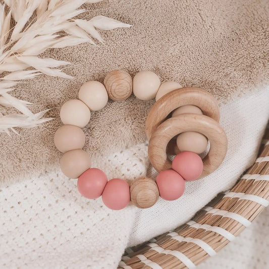 Siliconen bijtring in beige en oud roze met houten ringen en kralen.