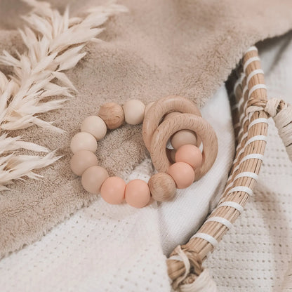 Siliconen bijtring in beige en zalmkleur met houten ringen en kralen.