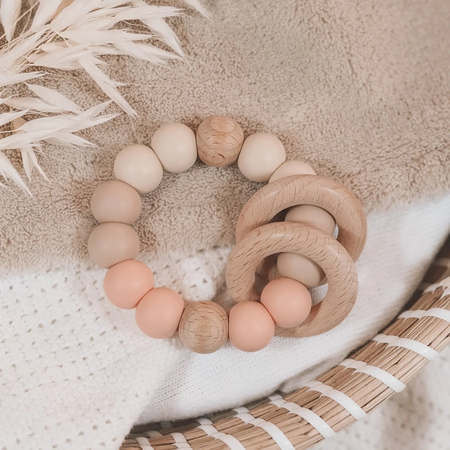 Siliconen bijtring in beige en zalmkleur met houten ringen en kralen.