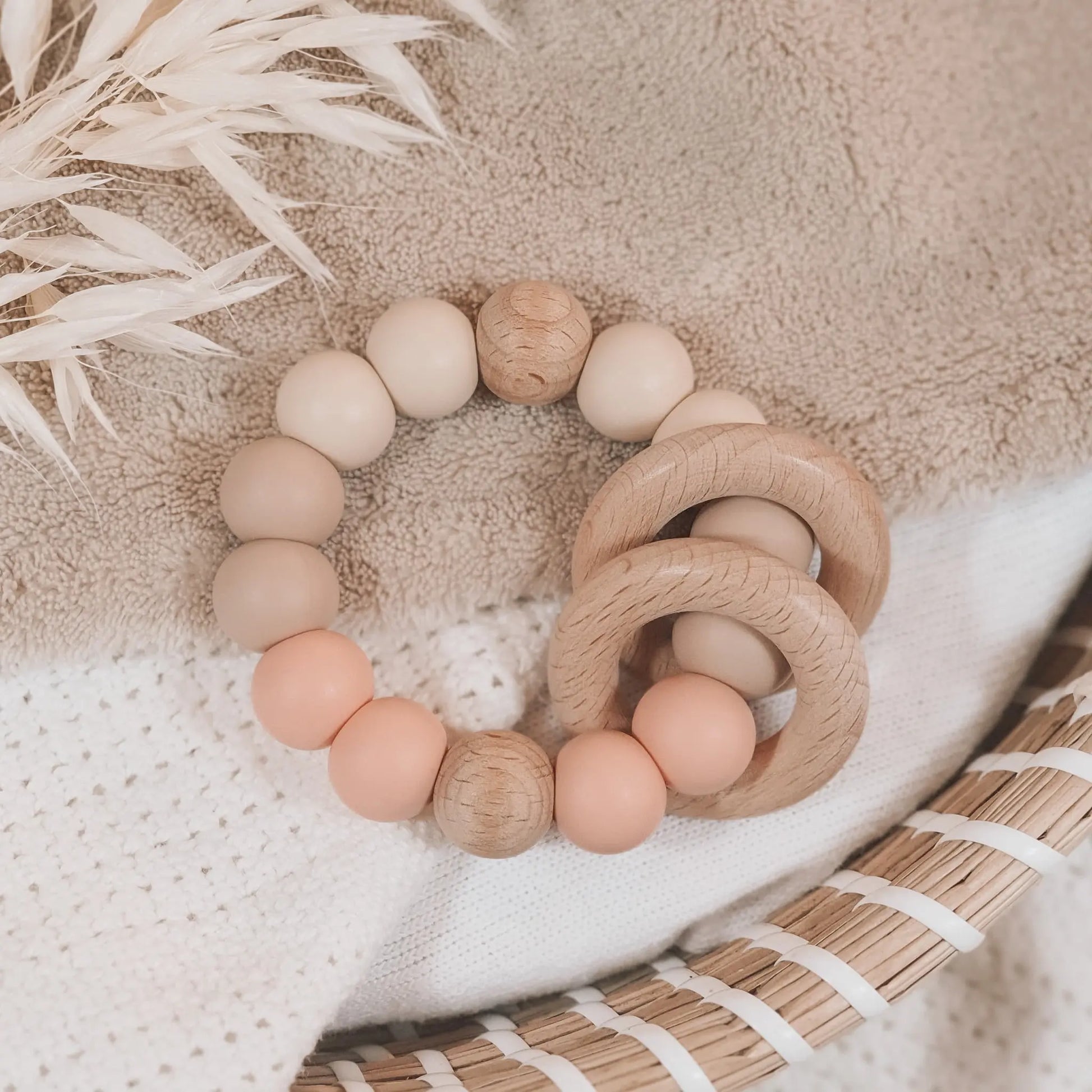 Siliconen bijtring in beige en zalmkleur met houten ringen en kralen.