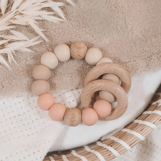 Siliconen bijtring in beige en zalmkleur met houten ringen en kralen.