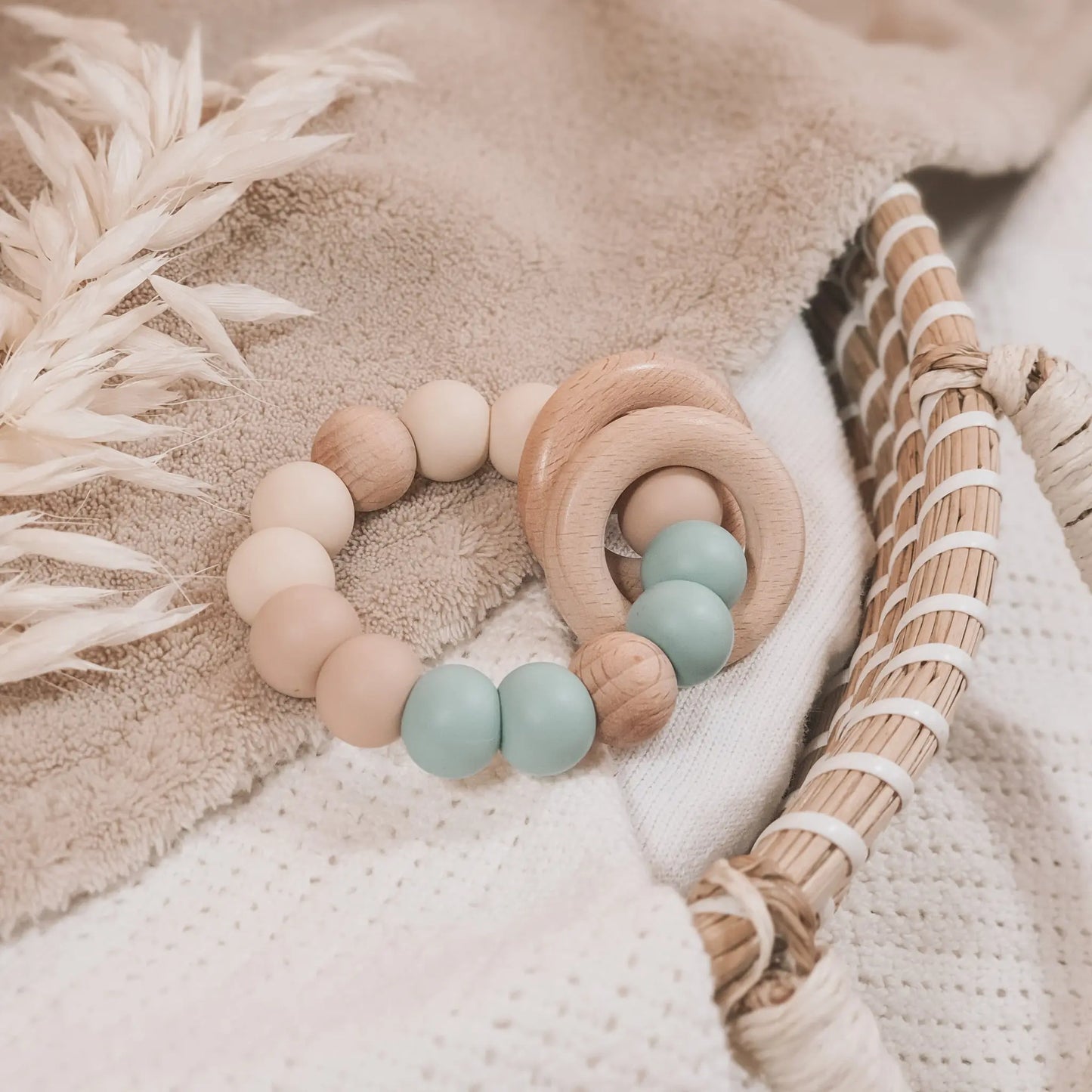 Siliconen bijtring in beige en blauw met houten ringen en kralen.