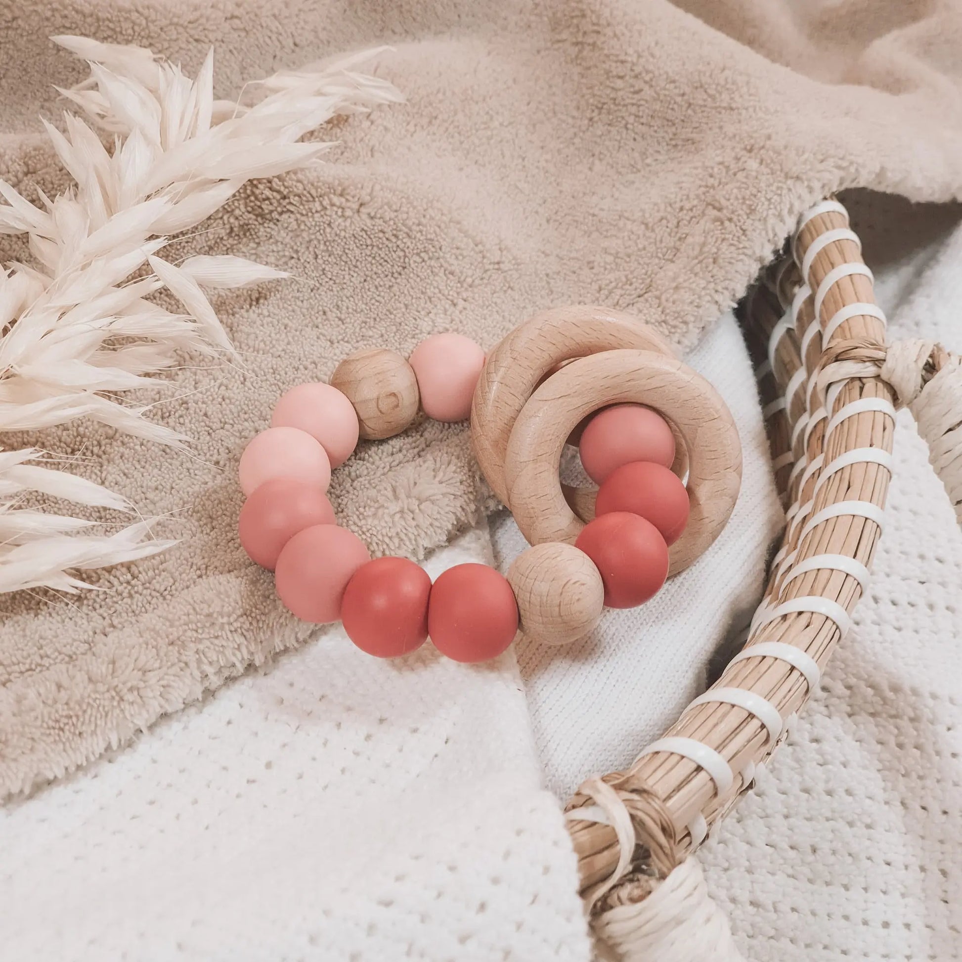 Siliconen bijtring in roze tinten en ombre effect met houten ringen en kralen.