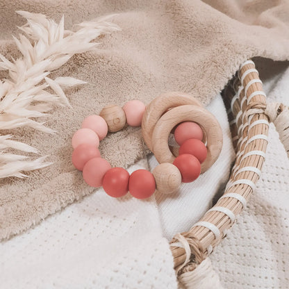 Siliconen bijtring in roze tinten en ombre effect met houten ringen en kralen.