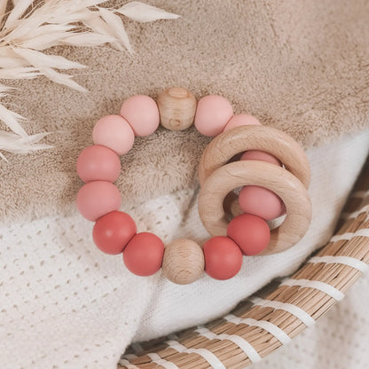Siliconen bijtring in roze tinten en ombre effect met houten ringen en kralen.