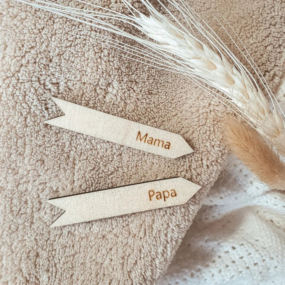 Houten groeipijltjes om je lengte bij te houden, gegraveerd met de teksten "papa" en "mama".