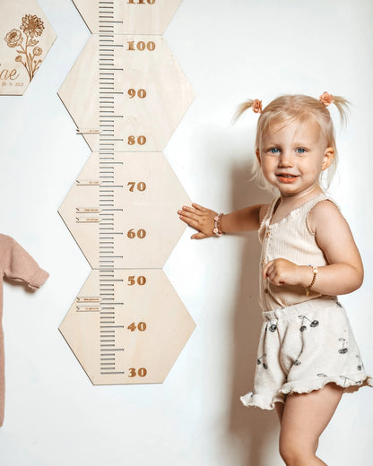 Jong meisje dat bij een houten groeimeter staat.