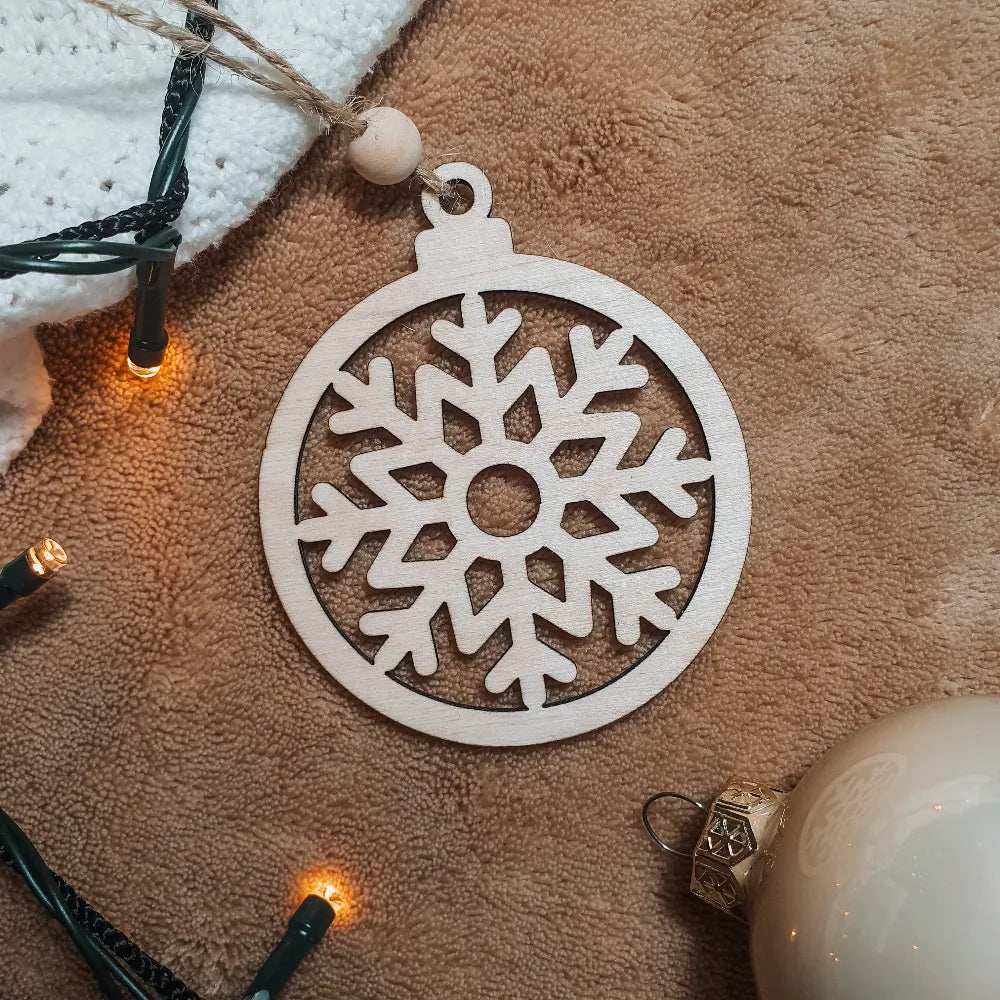 Houten kerstbal met uitgesneden sneeuwvlokje.