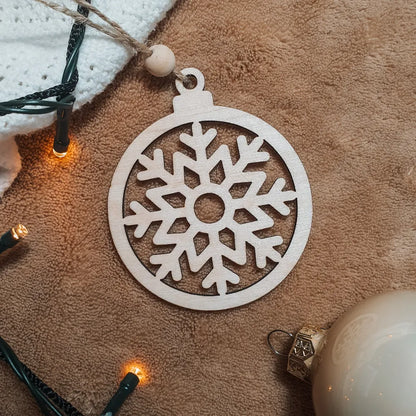 Houten kerstbal met uitgesneden sneeuwvlokje.