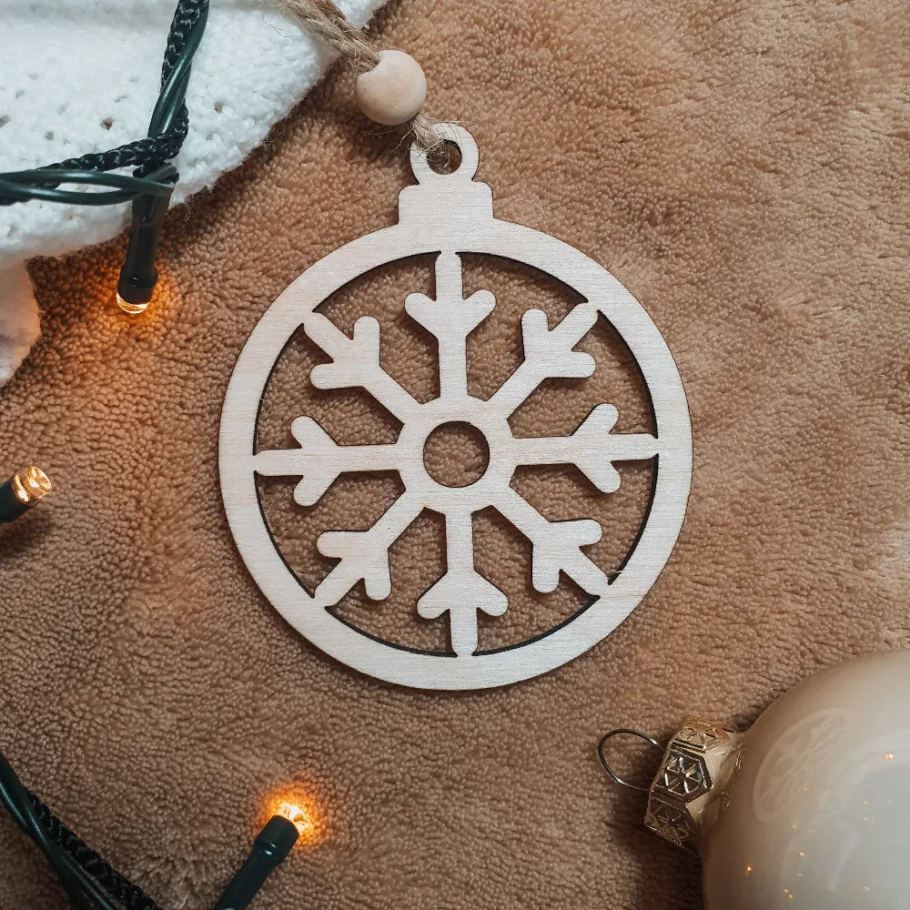 Houten kerstbal met uitgesneden sneeuwvlokje.