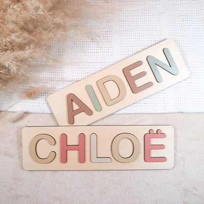 Gepersonaliseerde houten naampuzzel met pastelgekleurde letters, voorbeeld met de namen Aiden en Chloë.