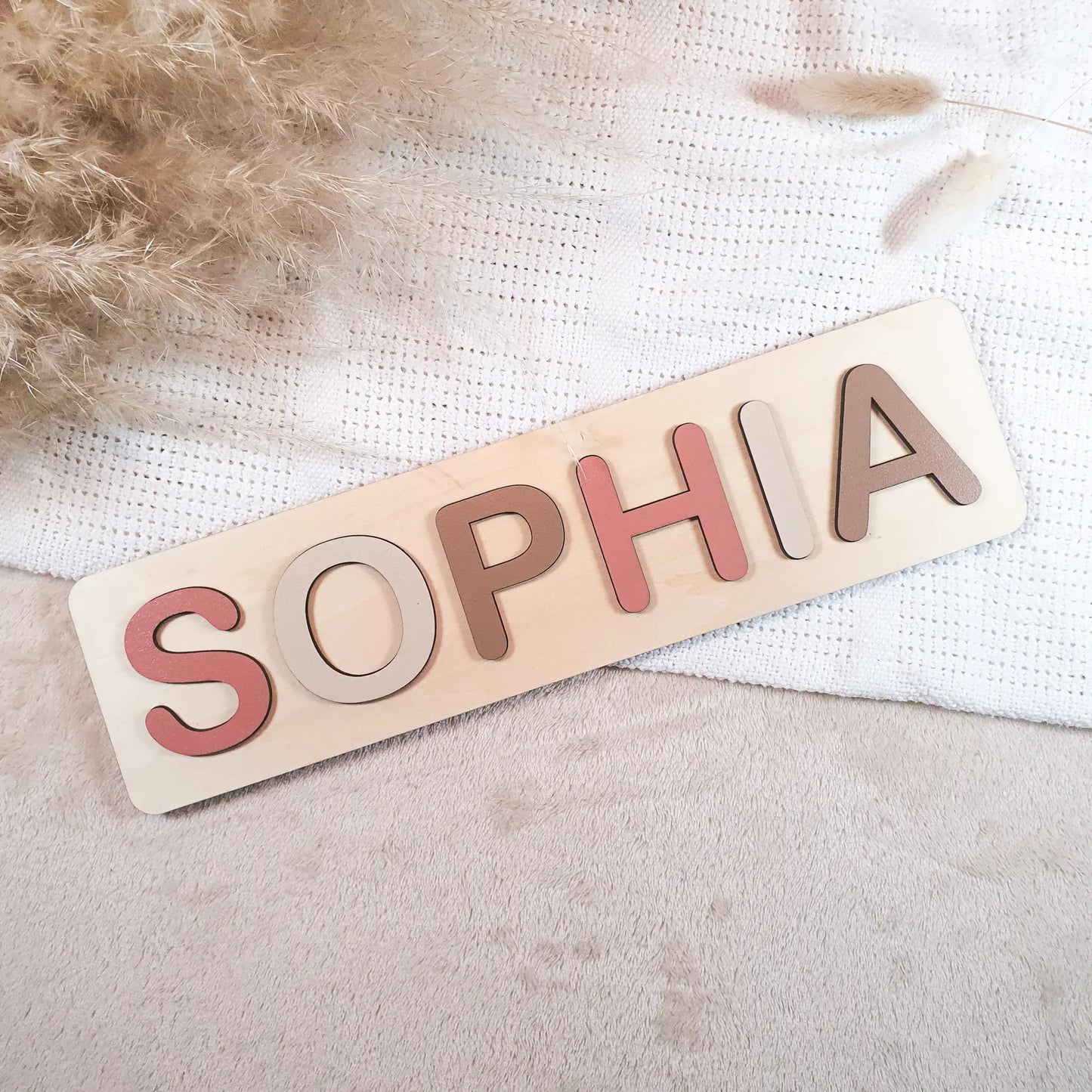 Gepersonaliseerde houten naampuzzel met pastelgekleurde letters, voorbeeld met de naam Sophia.