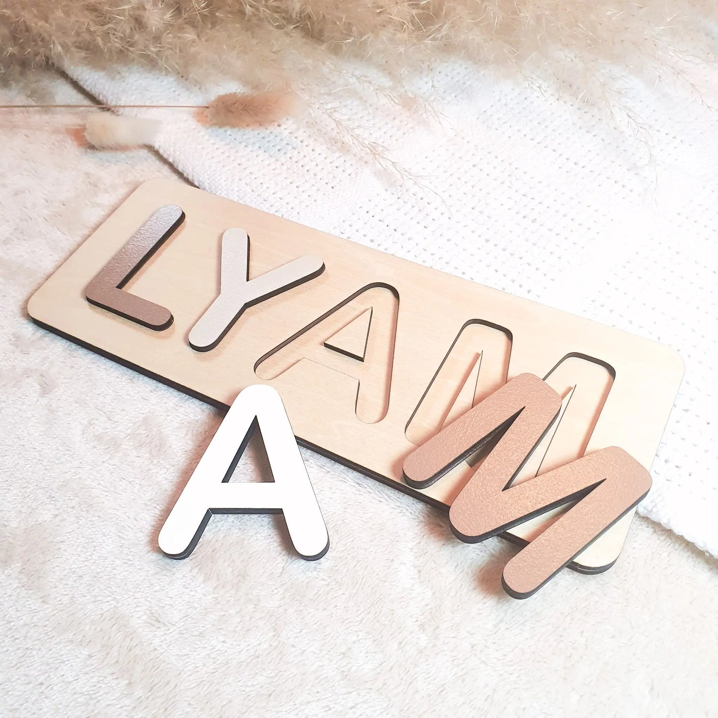 Gepersonaliseerde houten naampuzzel met pastelgekleurde letters, voorbeeld met de naam Lyam.
