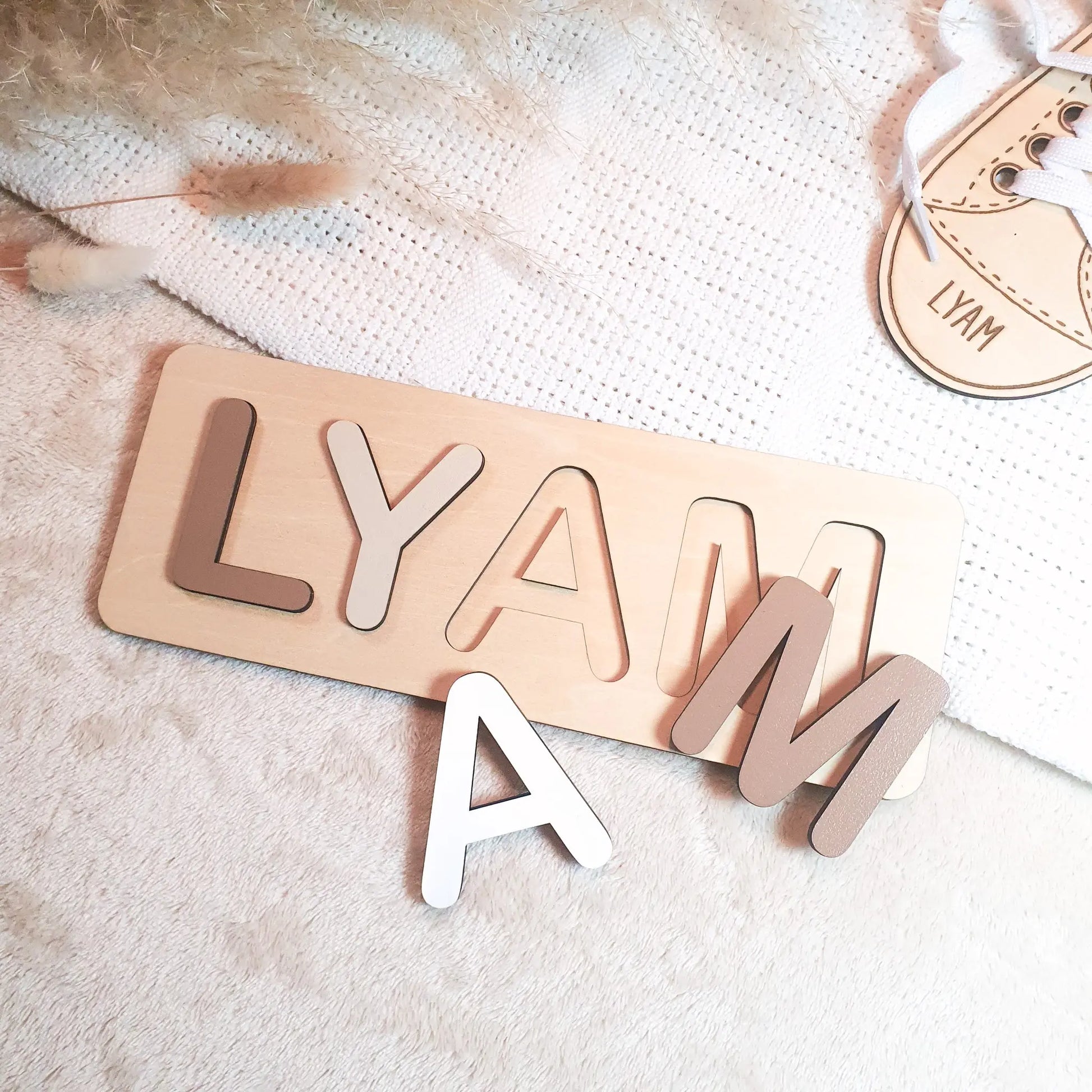 Gepersonaliseerde houten naampuzzel met pastelgekleurde letters, voorbeeld met de naam Lyam.