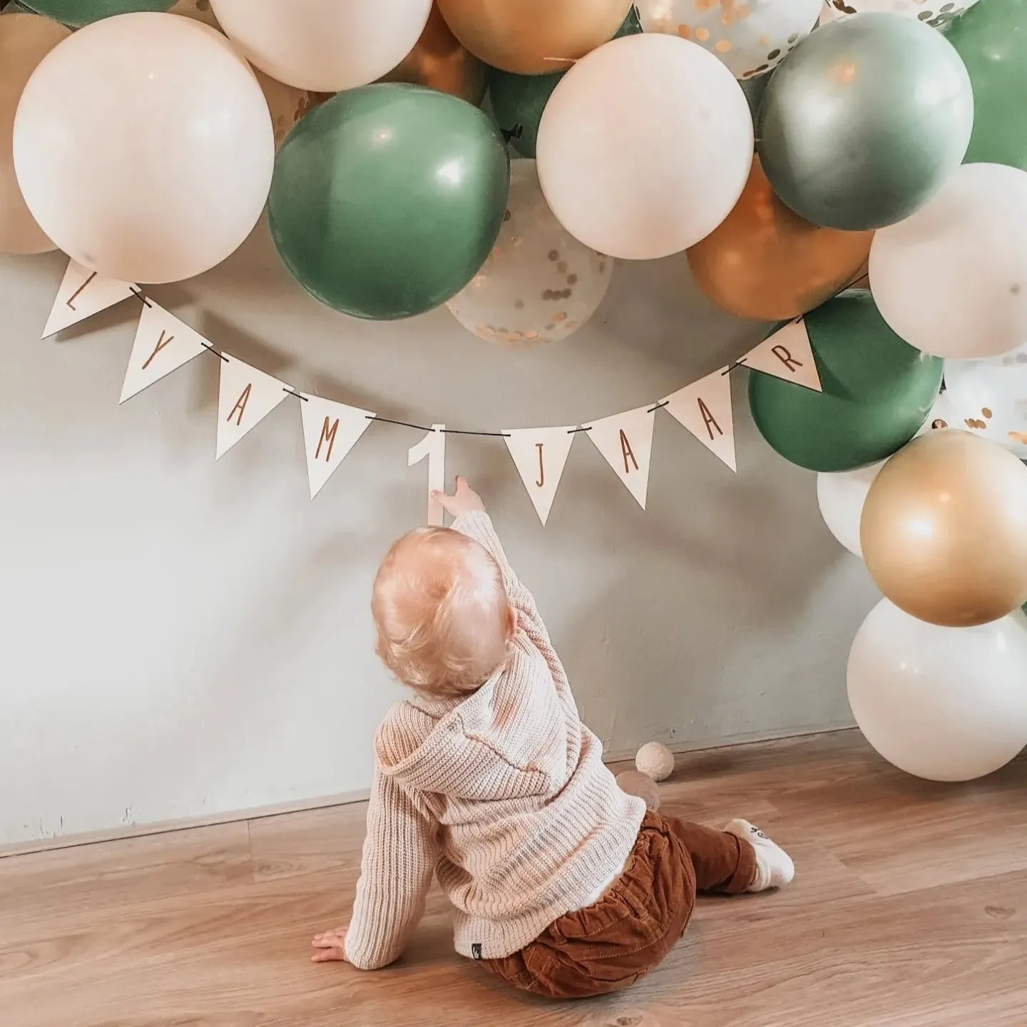 Dreumes bij een houten vlaggenlijn met naam en leeftijd voor een verjaardag.