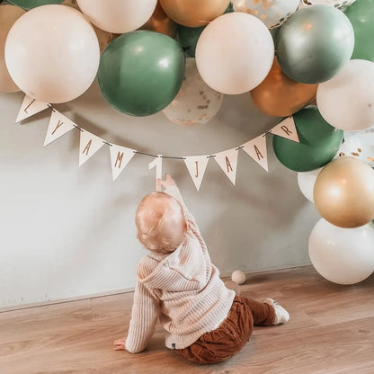 Dreumes bij een houten vlaggenlijn met naam en leeftijd voor een verjaardag.