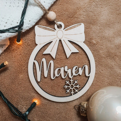 Houten kerstbal met strik, sneeuwvlokje en uitgesneden naam "Maren".