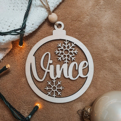 Houten kerstbal met de naam "Vince" en sneeuwvlokjes.