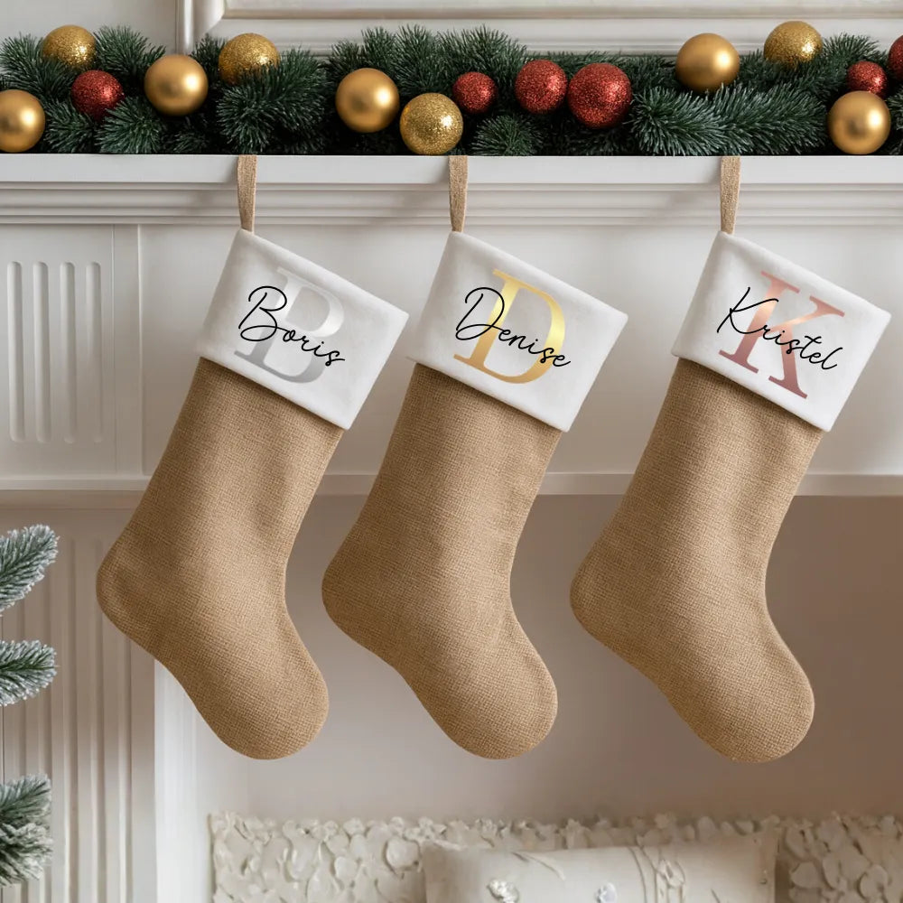 Gepersonaliseerde kerstsokken aan een schouw met naam en metallic monogram.