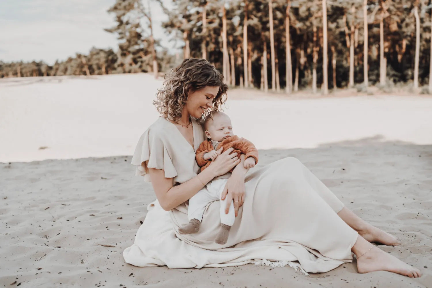 Moeder Madelaine met zoontje Lyam, zittend op de grond in het zand.