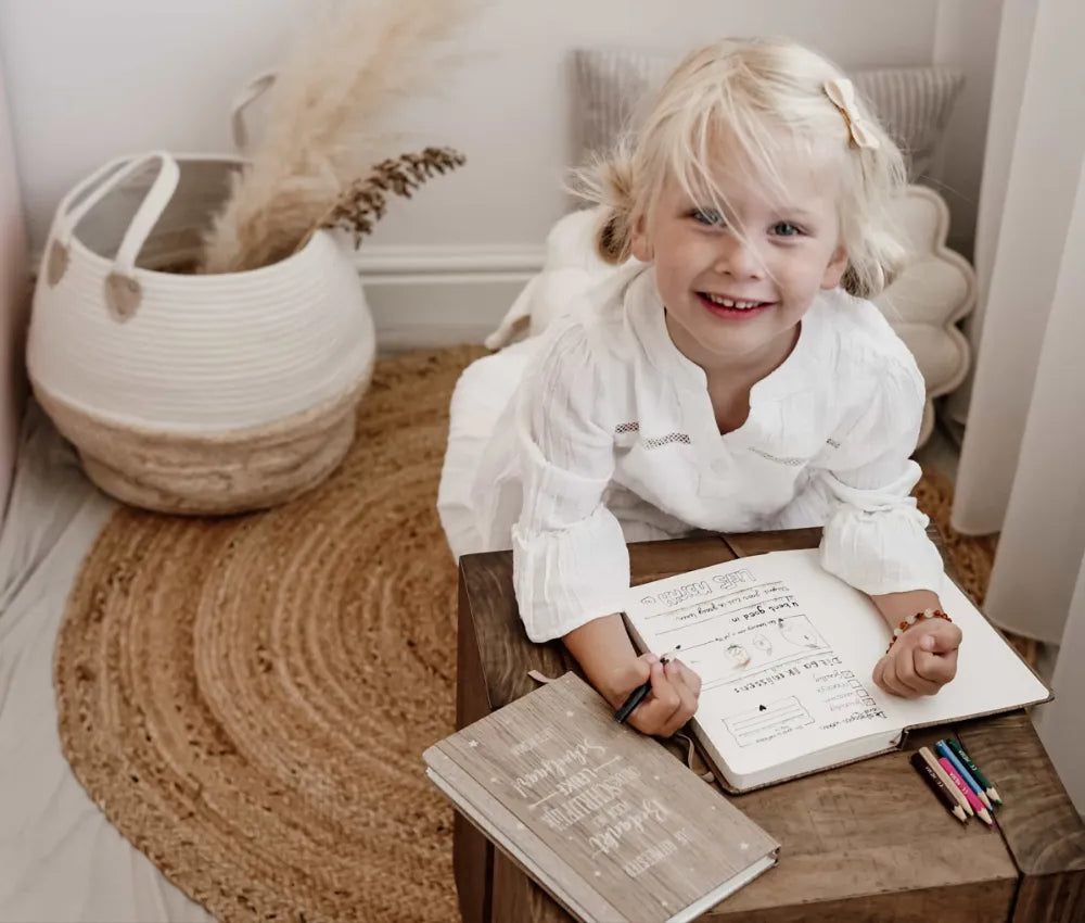 Jong meisje dat in een gepersonaliseerd notitieboekje voor juf schrijft.