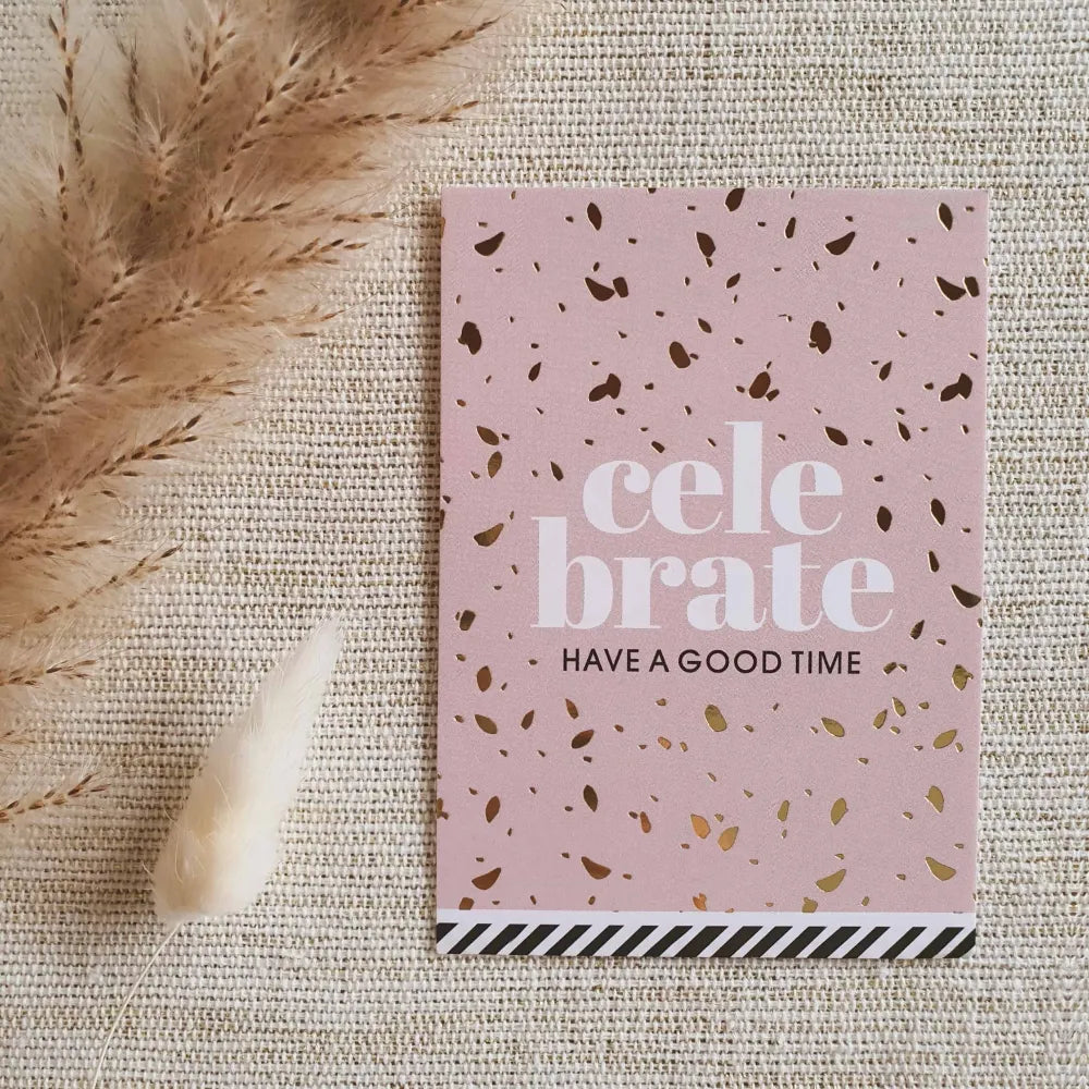 Roze kaartje met de tekst 'Celebrate, hava a good time' en goud bedrukte confetti.