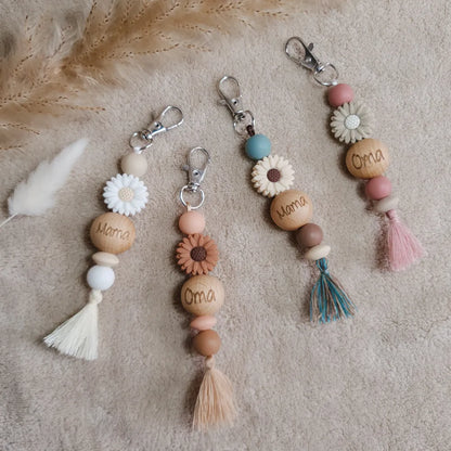 Sleutelhangers met siliconen kralen, een bloem en een kwastje en 'mama' of 'oma' gegraveerd op een houten kraal.