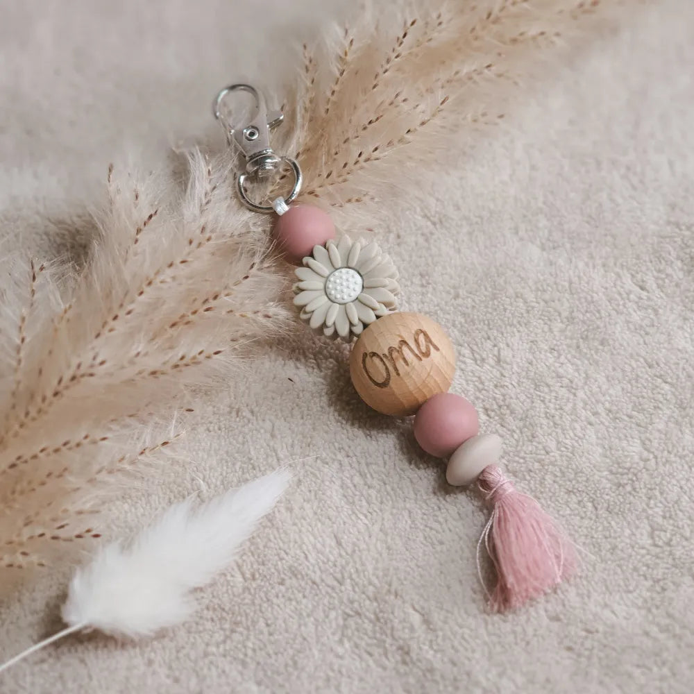 Sleutelhanger met roze en taupe kleurige siliconen kralen, een taupe bloem en een roze kwastje, met 'oma' gegraveerd op een houten kraal.