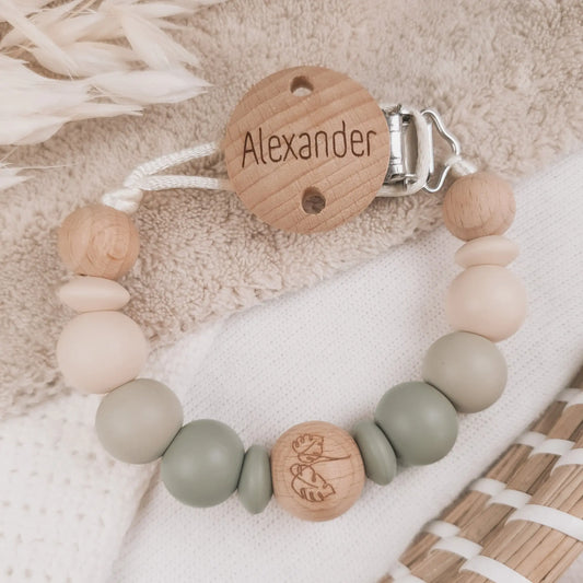 Gepersonaliseerd speenkoord met naam gegraveerd op de clip en siliconen kralen in beige en groen met houten details.