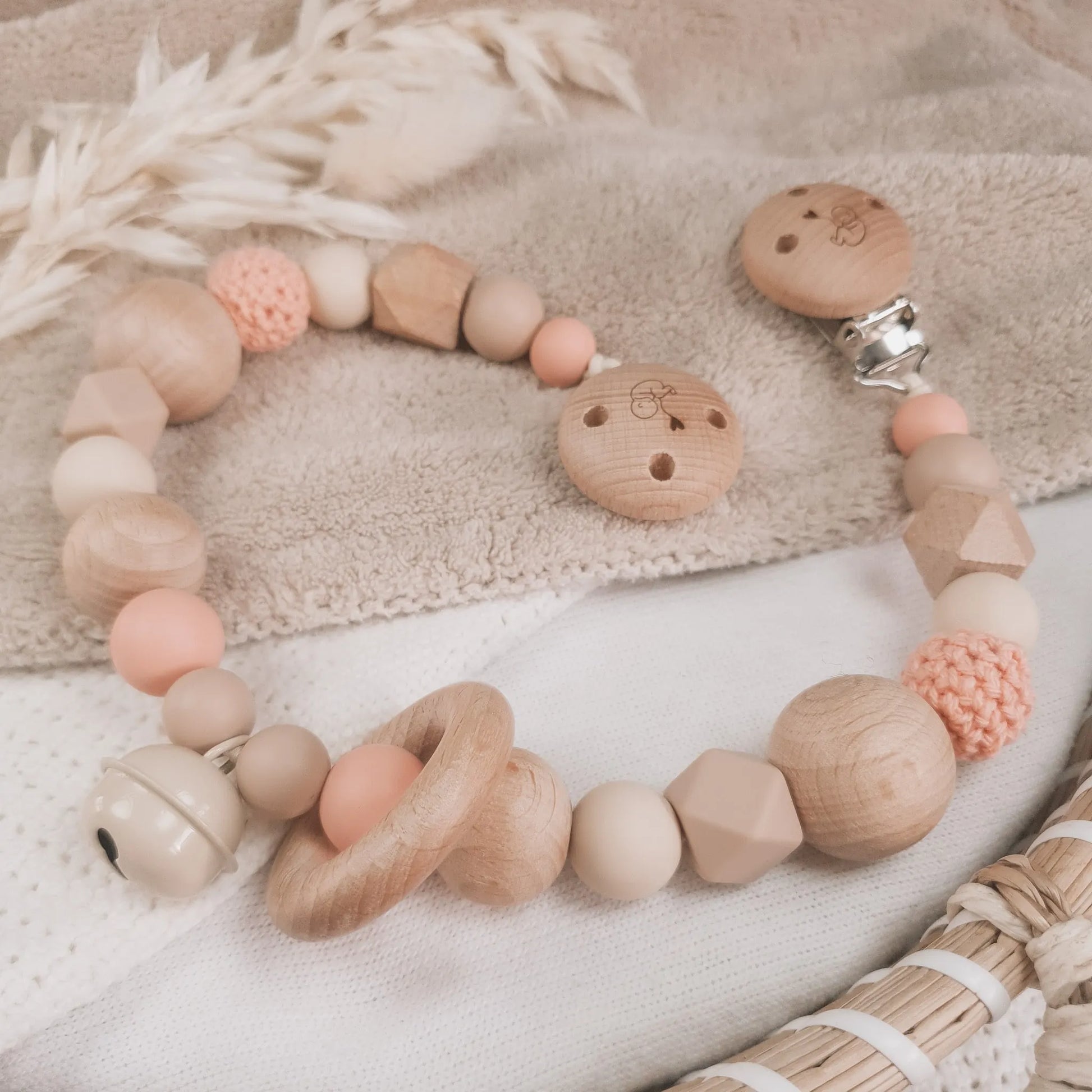 Wagenspanner in beige en zalmkleur met siliconen en houten kralen.