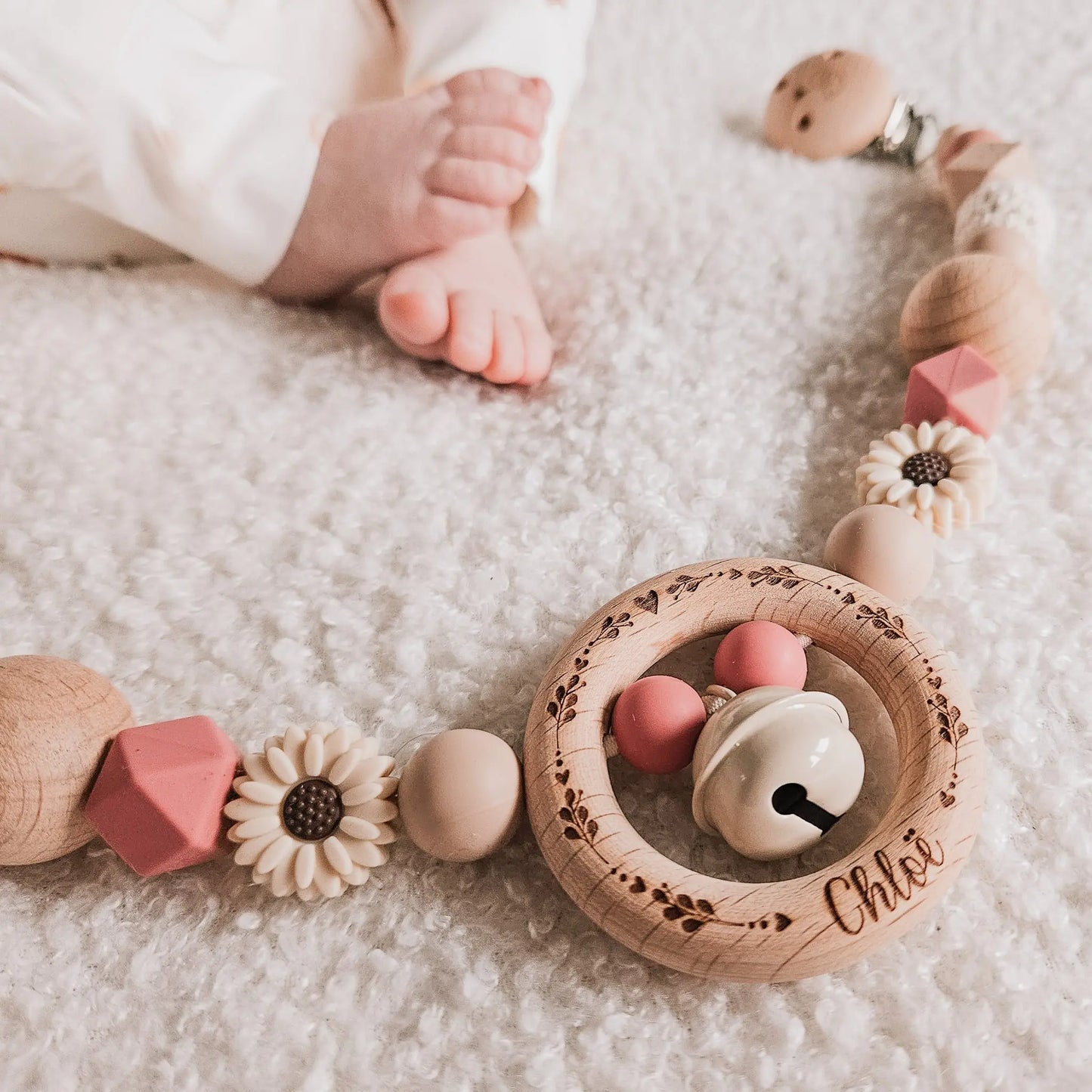 Babyvoetjes met een gepersonaliseerde roze wagenspanner, met hartjes, takjes en naam gegraveerd op de houten clip.